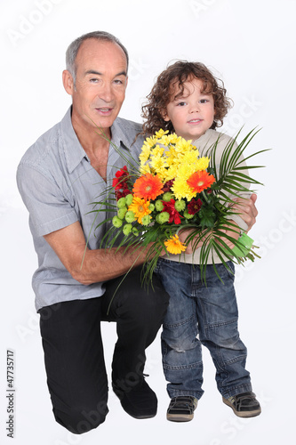 Photo: a grandfather and his little son holding a flowers bouquet a grandfather and his little son holding a flowers bouquet