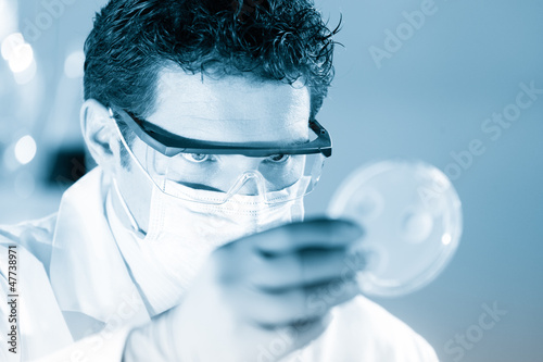 Photo: Scientist observing petri dish. Scientist observing petri dish.