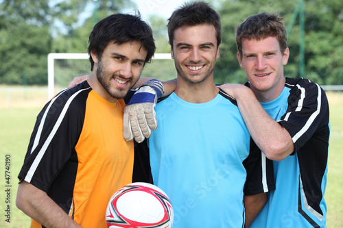 Photo: three football players in casual clothes posing for the photo three football players in casual clothes posing for the photo