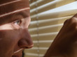 Foto: Man looking through blinds Man looking through blinds