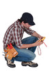 A kneeled electrician with a voltmeter.