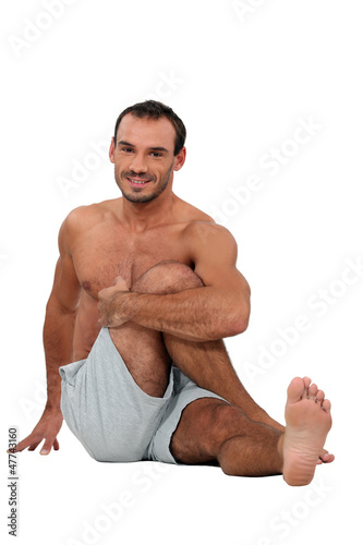 Photo: Man sat on the floor stretching Man sat on the floor stretching