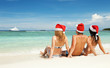 Photo: Happy friends in santa hats on the beach. Christmas vacation Happy friends in santa hats on the beach. Christmas vacation