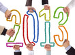 Hands holding bricks forming year 2013