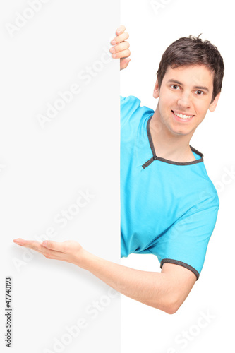Photo: A smiling handsome male gesturing behind a panel A smiling handsome male gesturing behind a panel