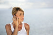 Blond woman making at call at the coast