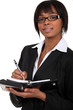 A businesswoman taking notes on a planner.