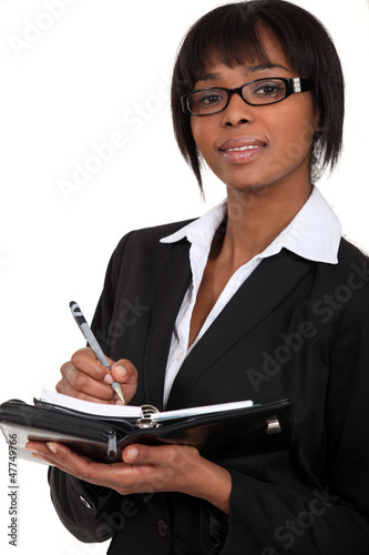 Photo: A businesswoman taking notes on a planner. A businesswoman taking notes on a planner.