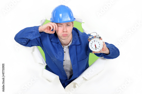 Photo: Bleary eyed construction worker with an alarm clock Bleary eyed construction worker with an alarm clock