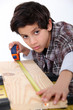 Young boy measuring a plank of wood
