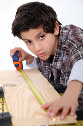 Photo: Young boy measuring a plank of wood Young boy measuring a plank of wood