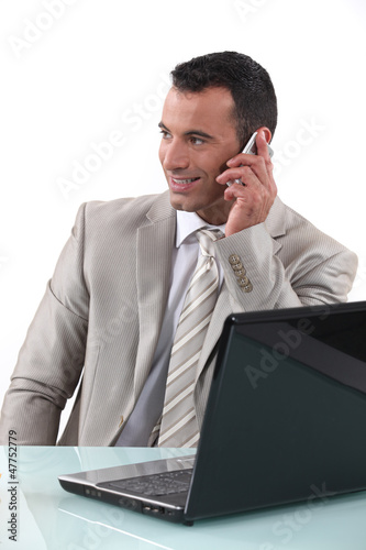 Photo: Worker on the phone in front of computer Worker on the phone in front of computer