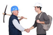 A construction worker and his trainee shaking hands.