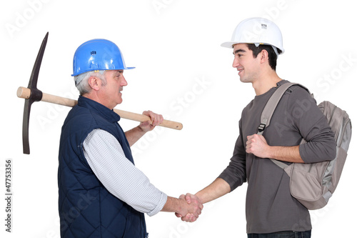Photo: A construction worker and his trainee shaking hands. A construction worker and his trainee shaking hands.