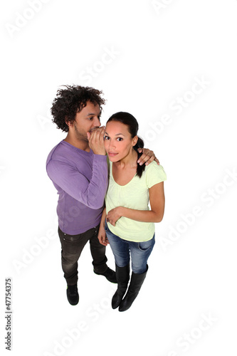 Photo: Man whispering secret to young woman Man whispering secret to young woman