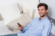 Photo: Young man using cellphone on couch Young man using cellphone on couch