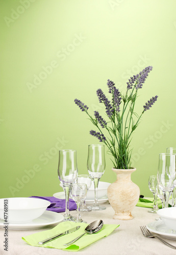 Photo: Table setting in violet and green tones on color background Table setting in violet and green tones on color background