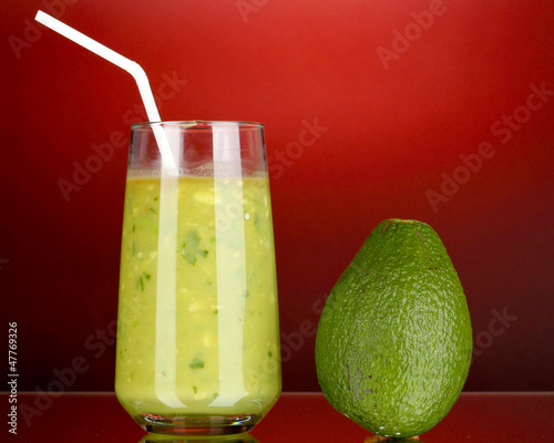 Photo: Useful fresh avocado on dark red background Useful fresh avocado on dark red background