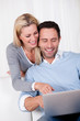 Couple laughing over information on a tablet