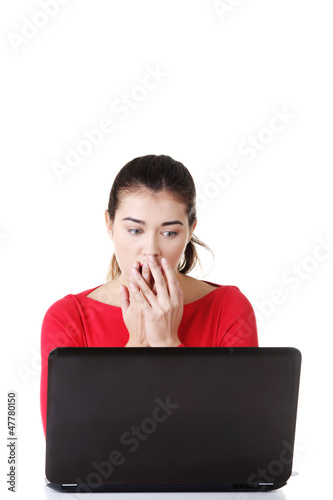 Photo: Surprised and disgusted woman working on laptop. Surprised and disgusted woman working on laptop.