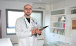 Doctor with clipboard and paperwork in his office