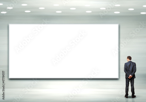 Photo: Business person standing near a blank billboard Business person standing near a blank billboard