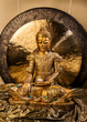 Goldener Buddha auf goldenem Kissen vor goldenem Gong