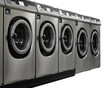 A row of industrial washing machines in a public laundromat
