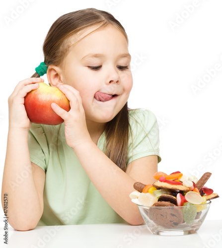 Photo: Little girl choosing between apples and sweets Little girl choosing between apples and sweets