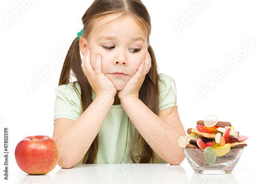 Photo: Little girl choosing between apples and sweets Little girl choosing between apples and sweets