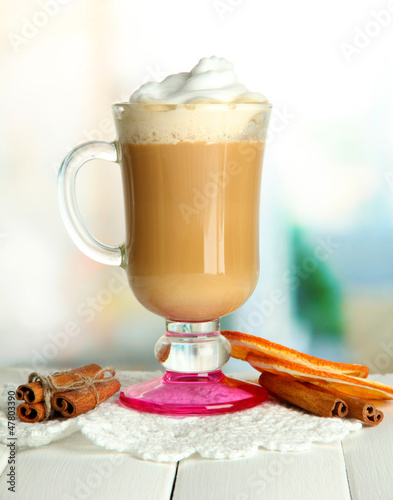 Photo: Fragrant coffee latte in glass cup with spices, on wooden table Fragrant coffee latte in glass cup with spices, on wooden table
