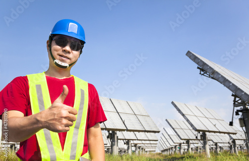Photo: happy worker with thumb up and standing before solar panel track happy worker with thumb up and standing before solar panel track