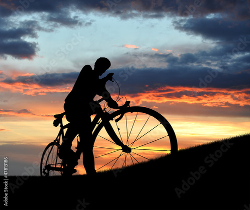 Photo: silhouette of the cyclist on road bike at sunset silhouette of the cyclist on road bike at sunset