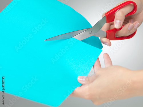 Photo: hands cutting a paper with scissors hands cutting a paper with scissors