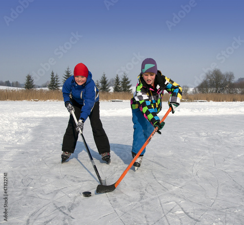 Photo: Zwei Jungen spielen Eishockey auf zugefrorenem See Zwei Jungen spielen Eishockey auf zugefrorenem See