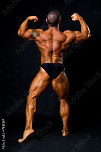 Photo: Tanned bodybuilder shows muscles of arms and back Tanned bodybuilder shows muscles of arms and back