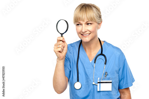 Photo: Pretty physician looking through magnifying glass Pretty physician looking through magnifying glass
