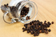 Black peppers and container on wooden table