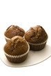 Three gingerbread muffins in cups on a plate.