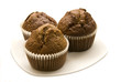 Three gingerbread muffins in cups on a plate.
