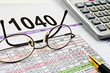 Tax forms with pen, calculator and glasses.