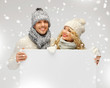 couple in a winter clothes holding blank board