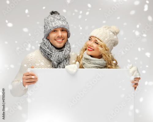 Photo: couple in a winter clothes holding blank board couple in a winter clothes holding blank board