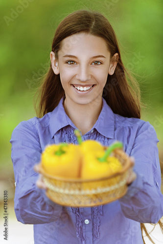 Photo: smiling teenage girl with basket of yellow peppers smiling teenage girl with basket of yellow peppers
