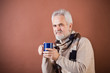 Smiling senior in scarf with a cup