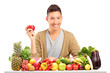 Handsome guy holding an apple on a table full of various food