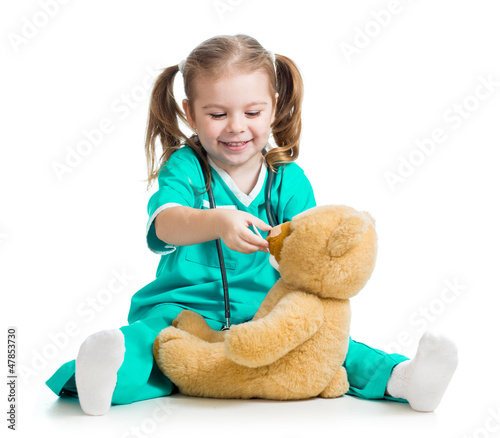 Photo: Adorable child with clothes of doctor and teddy bear over white Adorable child with clothes of doctor and teddy bear over white