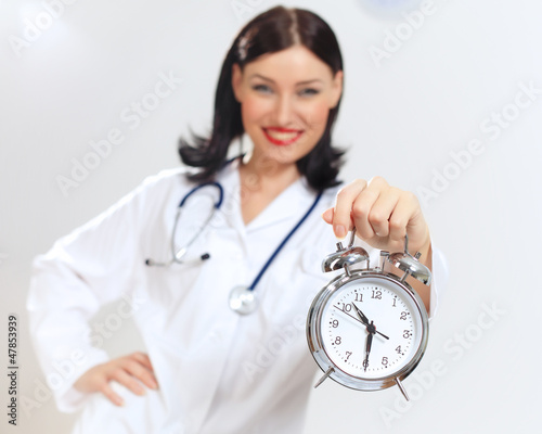 Photo: Young female doctor with clocks Young female doctor with clocks