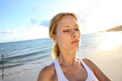 Photo: Beautiful woman doing yoga exercises by the beach Beautiful woman doing yoga exercises by the beach