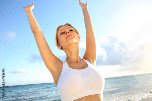 Photo: Beautiful woman doing yoga exercises by the beach Beautiful woman doing yoga exercises by the beach